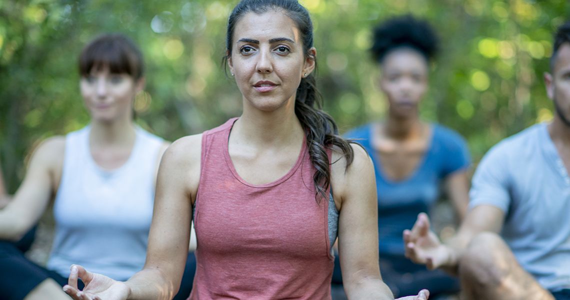 people doing yoga outdoors with trees in the background